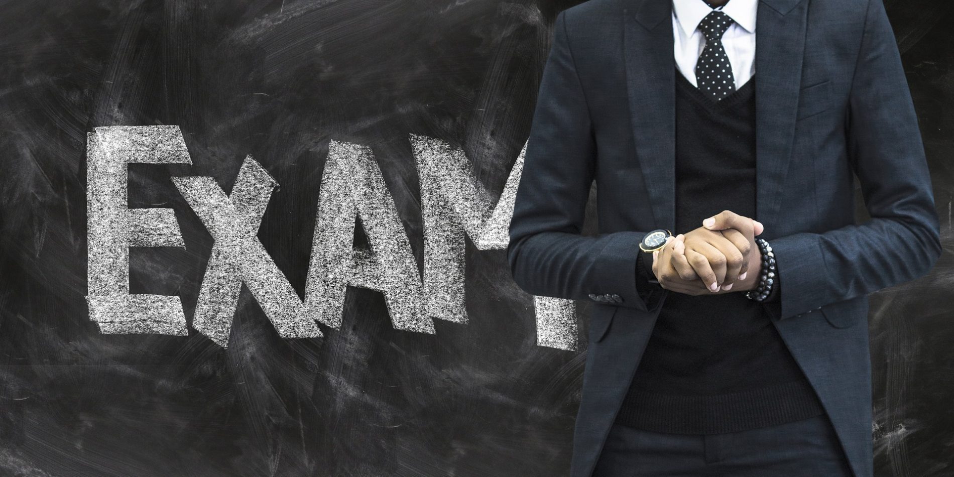 teacher standing in front of exam blackboard